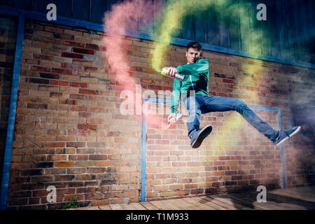 Portrait männliche moderne Tänzerin mit Sprühfarbe gegen Mauer Stockfoto