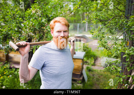 Portrait selbstbewusster, lächelnder Mann mit Schaufel im Garten Stockfoto