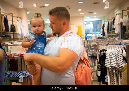 Vati mit Kind Mädchen wählt und kauft Kleidung im Store, Konzept der Vaterschaft. Stockfoto