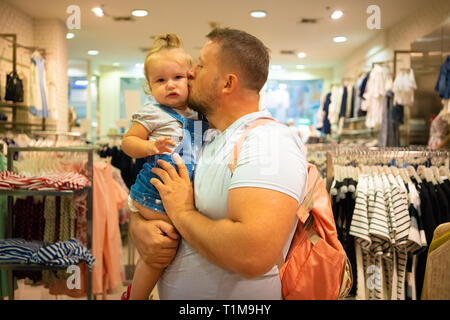 Vati mit Kind Mädchen wählt und kauft Kleidung im Store, Konzept der Vaterschaft. Stockfoto