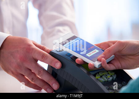 Wireless Payment mit Smartphone und der NFC-Technologie. Close Up. Kunden bezahlen mit Smart Phone in der Apotheke. Close Up shopping Stockfoto