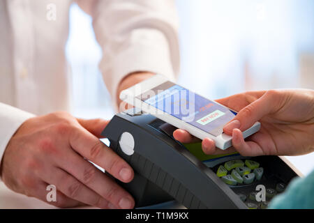 Wireless Payment mit Smartphone und der NFC-Technologie. Close Up. Kunden bezahlen mit Smart Phone in der Apotheke. Close Up shopping Stockfoto