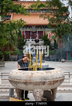 Beten mit Räucherstäbchen an Po Lin Kloster, Lantau Island, Hong Kong Stockfoto