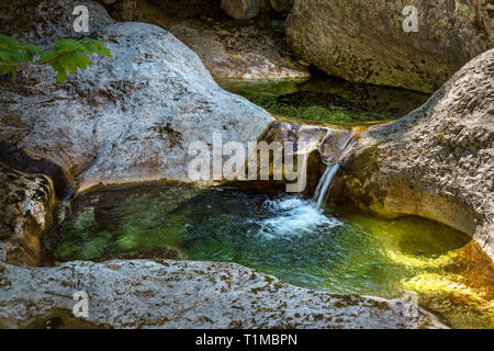 Kleiner Bach fließt sanft mit farbigen Felsen Stockfoto