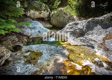 Kleiner Bach fließt sanft mit farbigen Felsen Stockfoto