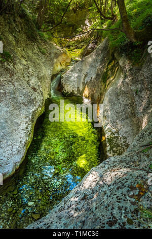 Kleiner Bach fließt sanft mit farbigen Felsen Stockfoto