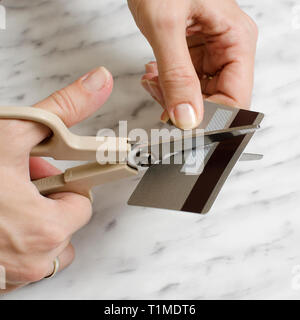 Weibliche Hände schneiden Kreditkarte mit Schere, in der Nähe Stockfoto