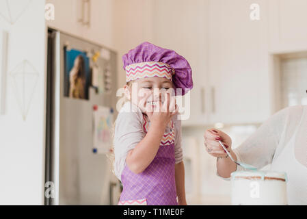 Glücklich, süße Mädchen in chefÕs hat Backen in der Küche Stockfoto