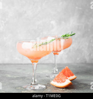 Trinken grapefruit Rosmarin und Eis im Glas Becher grau konkreten Hintergrund. Quadratischen Rahmen selektiven Fokus. Stockfoto