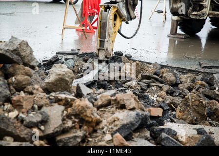 Reparatur von Kommunikation unter der Fahrbahn befindet. Straße Reparatur Auto bricht Asphalt Stockfoto