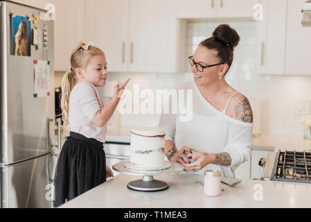 Mutter und Tochter dekorieren Kuchen in der Küche Stockfoto