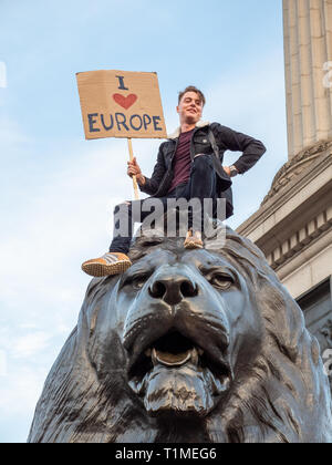 Junge Mann sitzt auf einem der Trafalgar Square Löwen halten "Ich liebe Europa'-Zeichen, während der Abstimmung März, 23. März 2019, London, UK Stockfoto