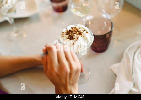 Die Frau Hände Verkostung und genießen Sie ein kaltes Dessert im Glas. Stockfoto