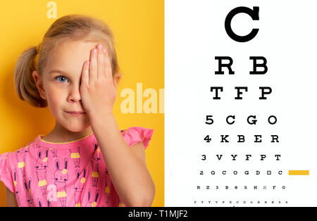 Überprüfung des Sehvermögens. Mädchen Abdecken eines Auges mit der Hand. Überprüfung des Sehvermögens ärztliche Untersuchungen. augenheilkunde Konzept. Kid ein Auge schliessen mit Hand gegen Alphabetisch unscharf Auge Test Grafik im Hintergrund. Stockfoto