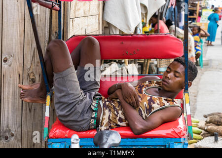 Toliara, Madagaskar - 10. Januar 2019: Ein männlicher Madagassischen pousse pousse Fahrer ein Nickerchen im Freien in Toliara, Madagaskar. Stockfoto