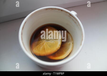 Weißes Porzellan Tasse mit heißem schwarzen Kaffee am Morgen mit zitronenscheibe in Stockfoto