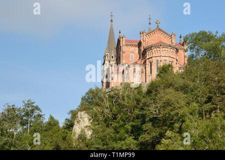 Basilica de Santa Maria La Real, von rosa Kalkstein gebaut, auf einem Baum bedeckte Hügel, Covadonga, Picos de Europa, Asturien, Spanien, August. Stockfoto