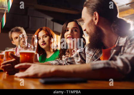Freundin mit roten Lippen an ihren bärtigen Mann in der Bar auf der Suche Stockfoto