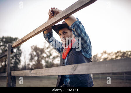 Cowboy in Leder Jacke und Hut wirft auf Ranch Stockfoto