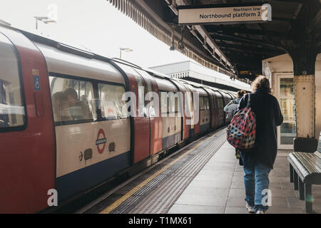 London, UK, 23. März 2019: Frau hinter den Zug im Freien auf der Plattform der Golders Green Tube Station. Die Londoner U-Bahn ist die älteste der Unte Stockfoto