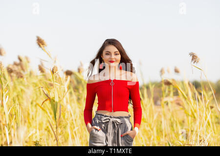 Einen schönen weiblichen kaukasischen High School Girl in Red Top Pullover zu Fuß außerhalb in einem Bauernhof Feld Sommer. Stockfoto