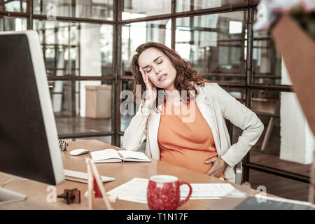 Müde, dunkelhaarige Frau über ihre Gesundheit gesorgt werden Stockfoto