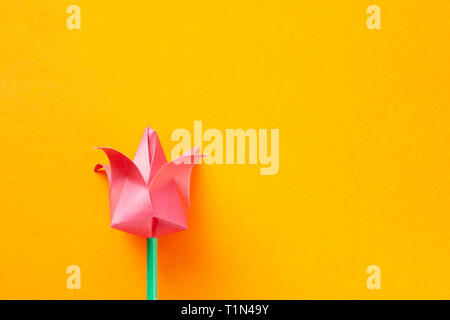 Rosa Papier tulip auf orangem Hintergrund. 8. März und den Frauentag Konzept. Handgefertigte origami Tulip mit Copyspace Stockfoto