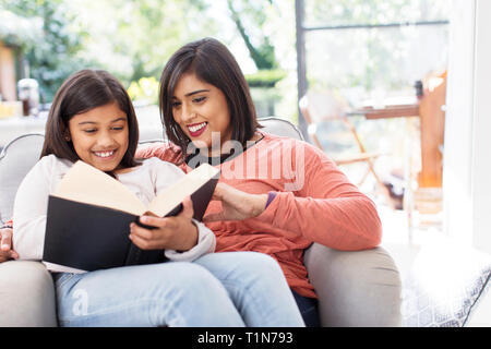 Mutter und Tochter lesen Buchen Sie im Sessel Stockfoto