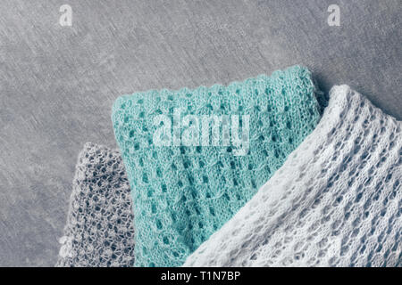 Stilvolle gestrickt, Taupe, Weiß und Minze farbigen Pullover in verschiedenen Strickmuster auf samtigen Gewebe angehäuft. Ansicht von oben, kopieren. Stockfoto