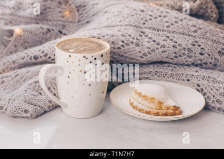 Stapel von warmen gemütlichen knitwears und eine Tasse Kaffee auf weißem Marmor Fensterbänke gegen weiße Fenster Hintergrund. Kopieren Sie Platz. Stockfoto