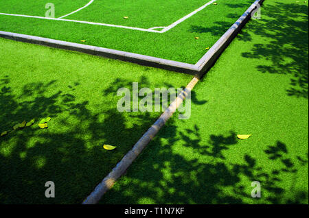 Textur aus Kunststoff künstliche Gras und der Schatten der Baum auf Fußballplatz Stockfoto