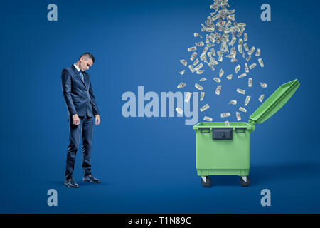 Traurig Geschäftsmann, die nächste Sitzung des Ständigen dumspter mit Regen von Dollar fallen, um sie zu öffnen. Stockfoto