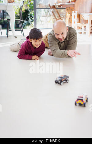 Vater und Sohn spielen mit Spielzeug Autos auf dem Boden Stockfoto