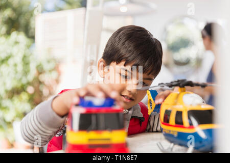 Jungen spielen mit Spielzeug Hubschrauber und Fire Engine Stockfoto