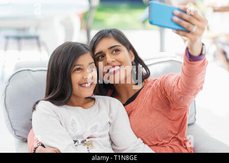 Glückliche Mutter und Tochter unter selfie mit smart phone in Sessel Stockfoto