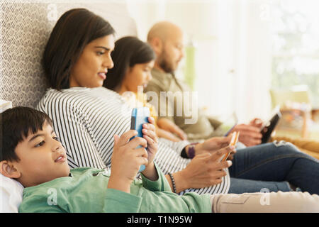 Familie mit Technologie auf dem Bett Stockfoto