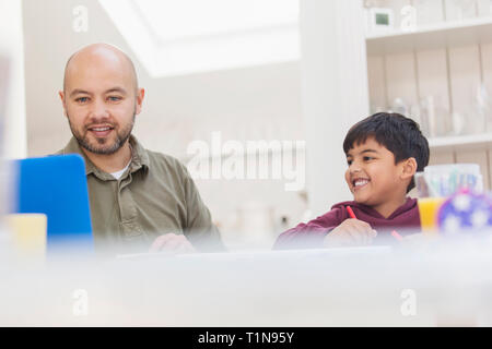 Vater und mit Laptop und Färbung am Tisch Sohn Stockfoto