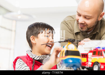 Vater und Sohn spielen mit Hubschrauber und Fire Engine Spielzeug Stockfoto