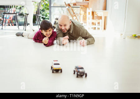 Vater und Sohn spielen mit Spielzeug Autos auf dem Boden Stockfoto