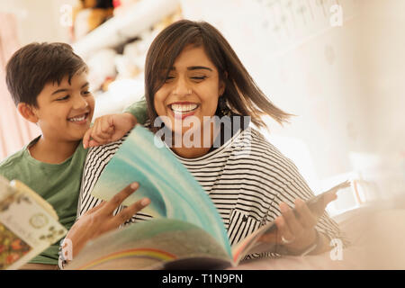 Glückliche Mutter und Sohn das Lesen von Büchern auf dem Bett Stockfoto