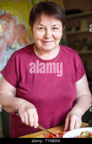 Portrait von erwachsenen Frau in der Küche Koteletts Gemüse für Salat. Stockfoto