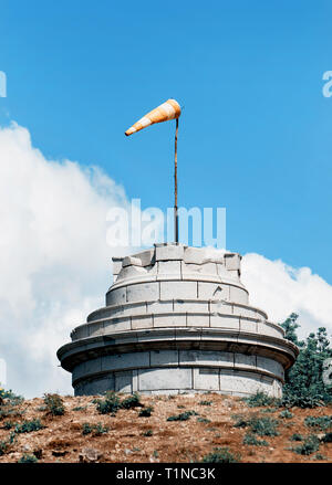 Windsack auf dem steinernen Turm zeigt die Windrichtung. Blaugrün und Orange Foto Filter. Stockfoto