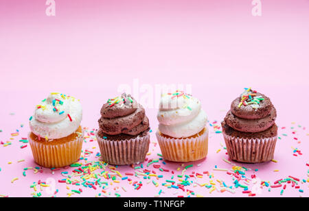 Cupcakes auf rosa Hintergrund. Vier cupcakes Vanille und Schokolade mit bunten Streuseln, kopieren Raum Stockfoto
