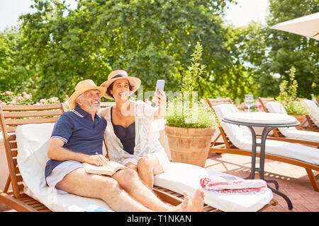 Gerne reifes Paar unter selfie mit Kamera Handy bei Sunny Resort Pool Stockfoto