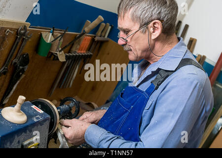 Ein älterer Mann mit Brille arbeiten an einer Drehmaschine in einer Schreinerei. Teilzeit- oder zusätzliche Einnahmen für die Rentner Stockfoto