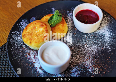 Quark Pfannkuchen mit Heidelbeeren und Minze zum Frühstück oder Mittagessen. Marmelade und Sauerrahm. Stockfoto