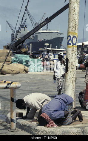 29th. Oktober 1993 Somalier beten in Richtung Mekka im neuen Hafen in Mogadischu, Somalia. Im Hintergrund das riesige Frachtschiff der US-Marine Administration, USNS Denebola. Stockfoto