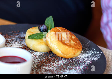 Quark Pfannkuchen mit Heidelbeeren und Minze zum Frühstück oder Mittagessen. Marmelade und Sauerrahm. Stockfoto