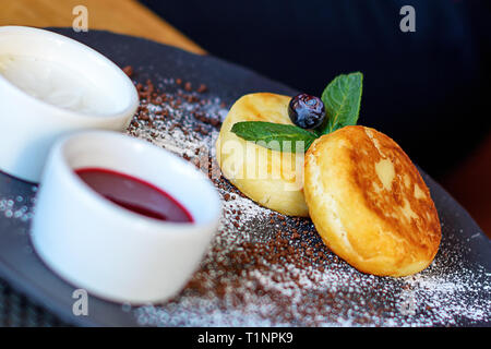 Quark Pfannkuchen mit Heidelbeeren und Minze zum Frühstück oder Mittagessen. Marmelade und Sauerrahm. Stockfoto