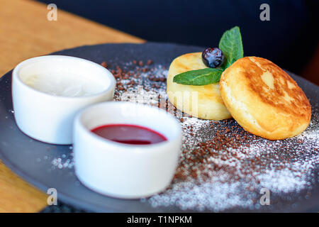 Quark Pfannkuchen mit Heidelbeeren und Minze zum Frühstück oder Mittagessen. Marmelade und Sauerrahm. Stockfoto